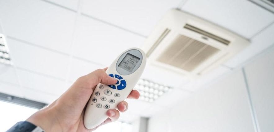 A man holding ac remote and operting